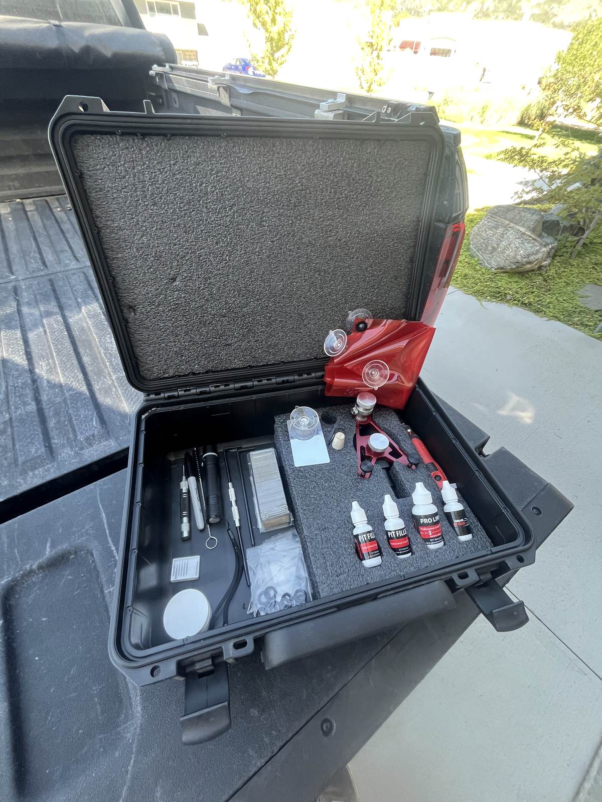 The repair kit open in a truck bed: injector bridge, resin bottles, curing tabs and probes, each in its own cutout.